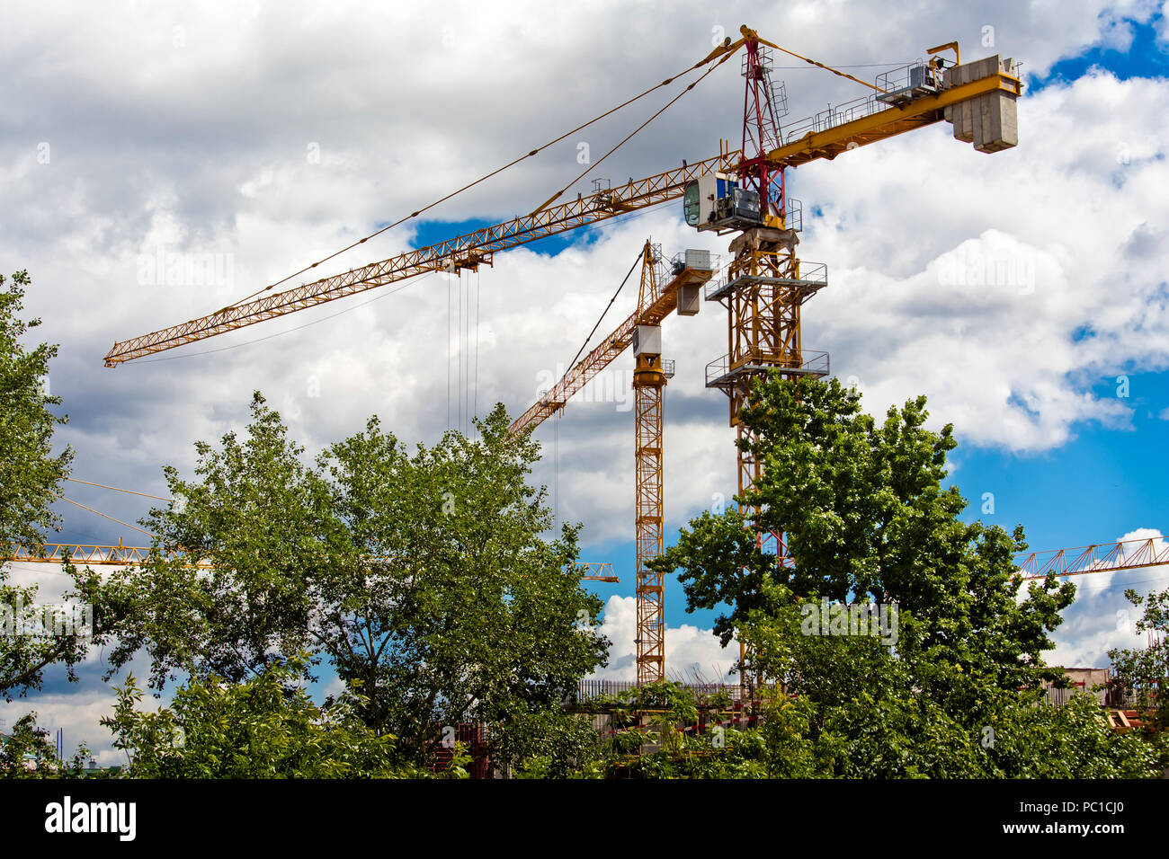 Two yellow building cranes on construction sites Stock Photo