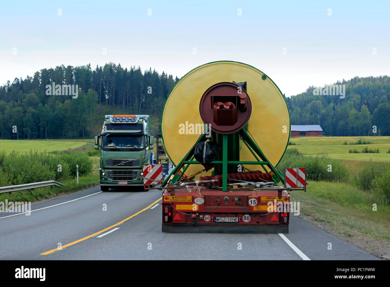 Rear view of oversize load transport by semi trailer of Peter-Star, Poland, passing a special transport truck on road. Salo, Finland - July 27, 2018. Stock Photo