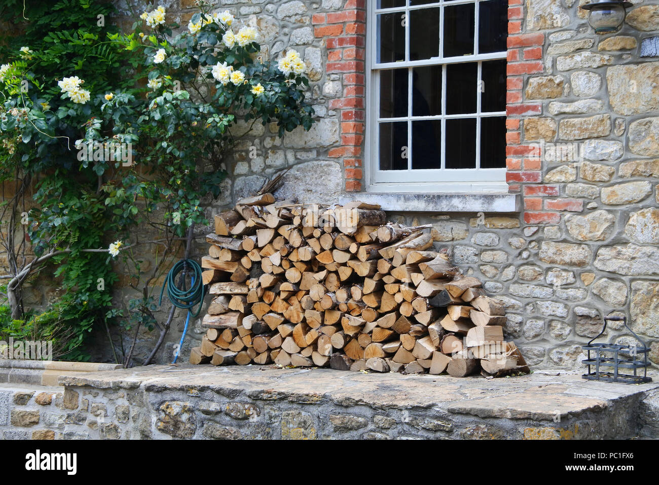 Stack of sawn logs outside a cottage - John Gollop Stock Photo