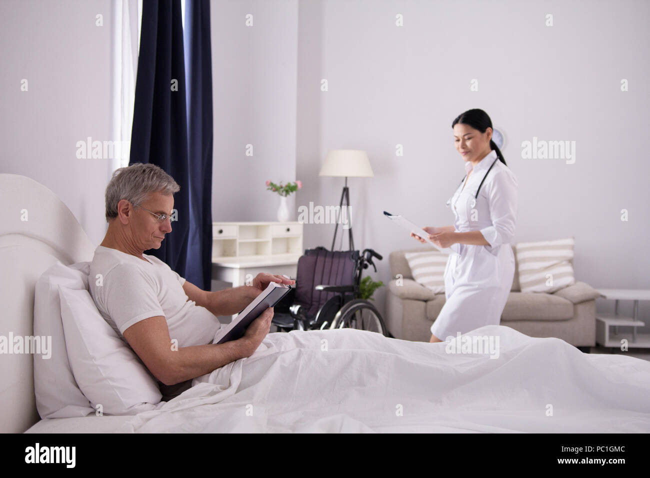 Disabled man reading in bed. Stock Photo