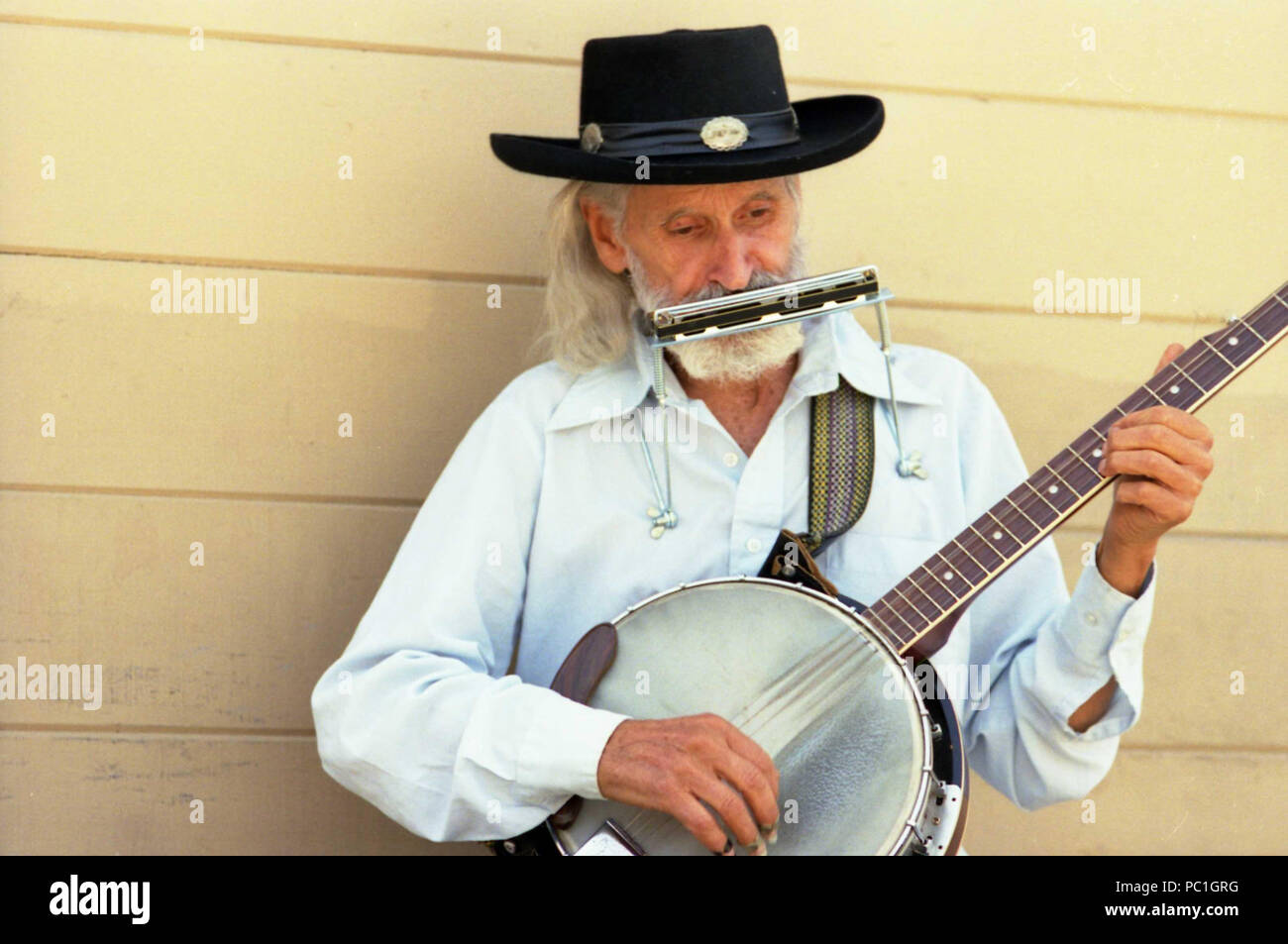 Man performing on the street, with banjo and harmonica Stock Photo