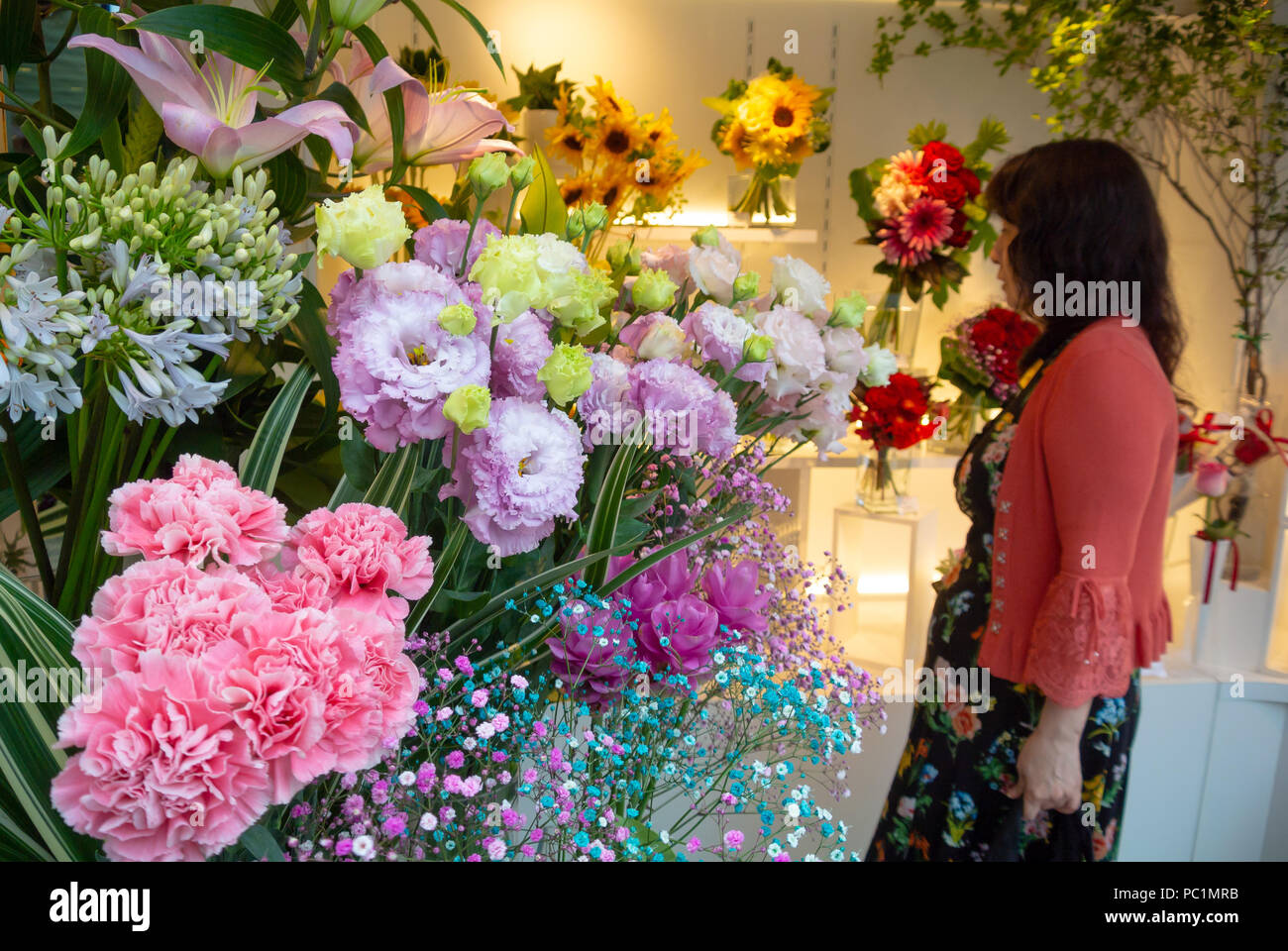 A Japanese woman choosing flowers at flower shop, Ginza, Tokyo, Japan Stock Photo