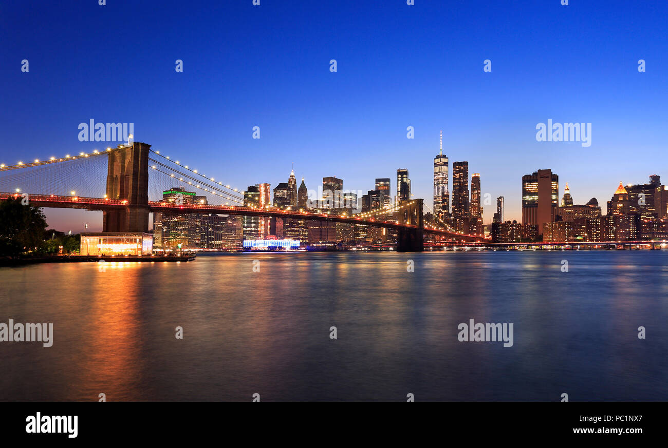 Panorama of Brooklyn Bridge and New York City (Lower Manhattan) with lights and reflections at dusk, USA Stock Photo