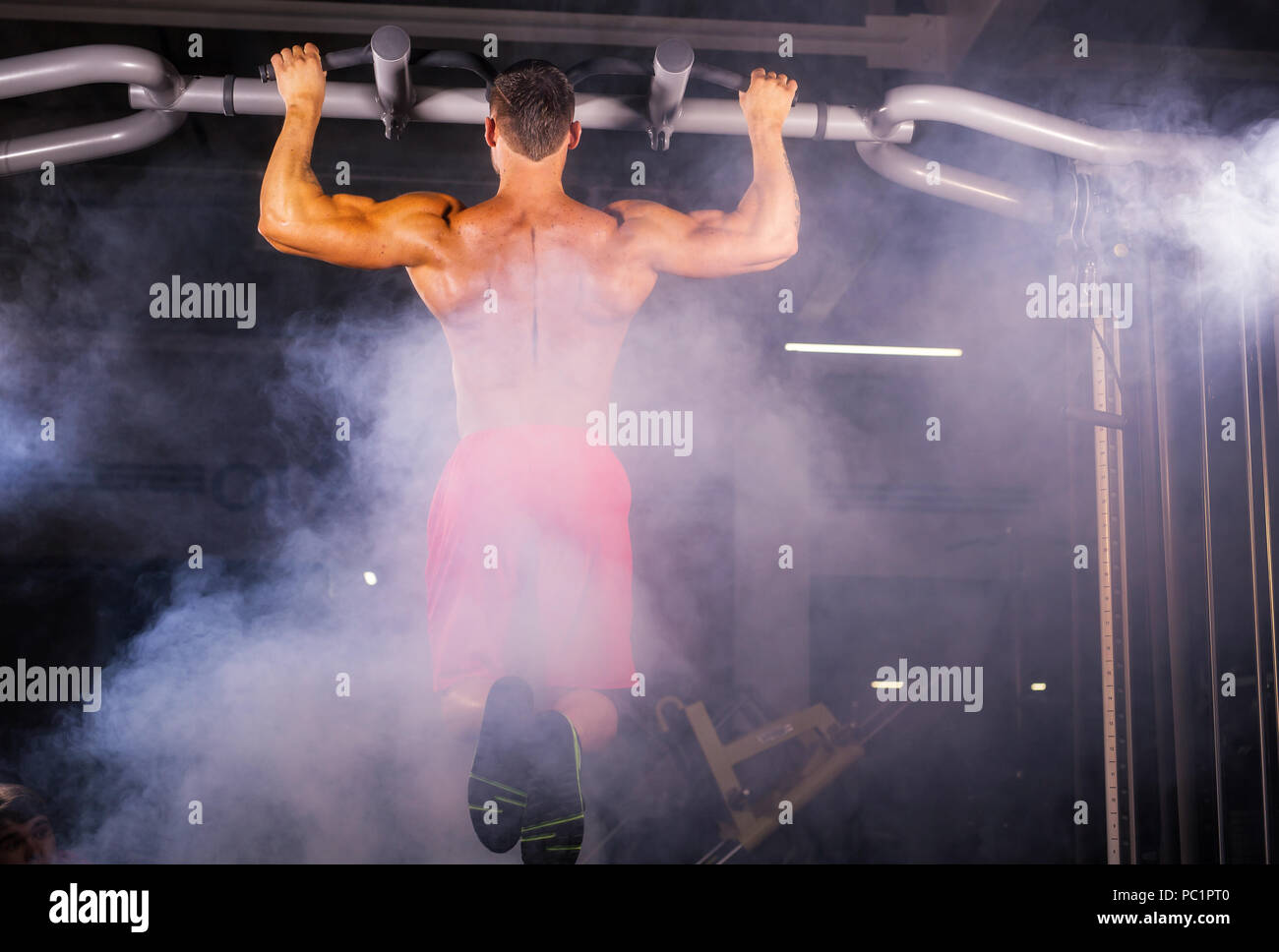 Strong young man doing pull up exercise on horizontal bar in gym Stock ...