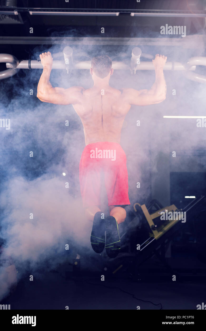 Strong young man doing pull up exercise on horizontal bar in gym Stock ...