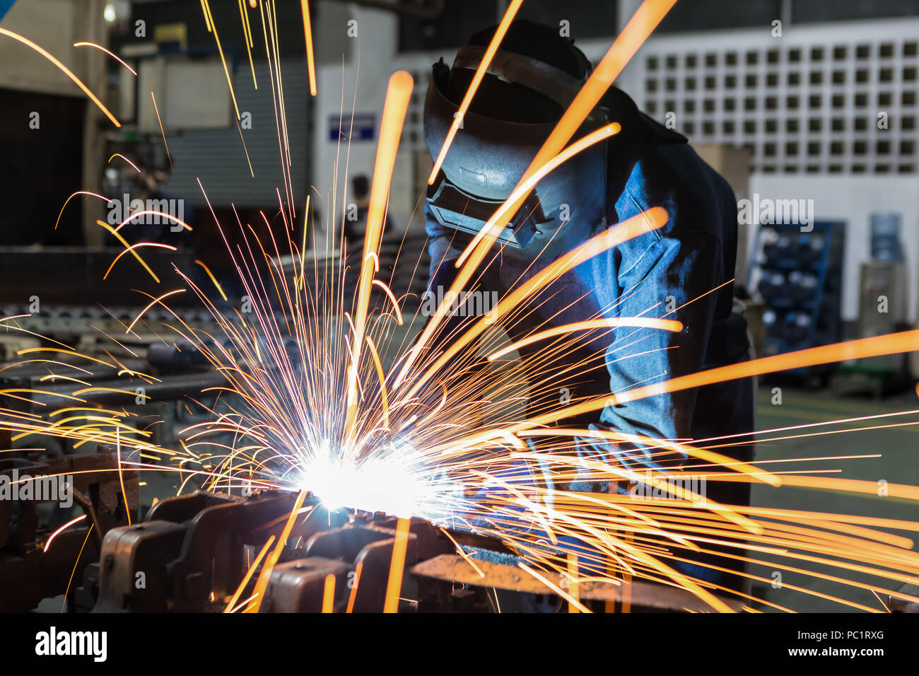 Worker is welding metal part with protective mask Stock Photo