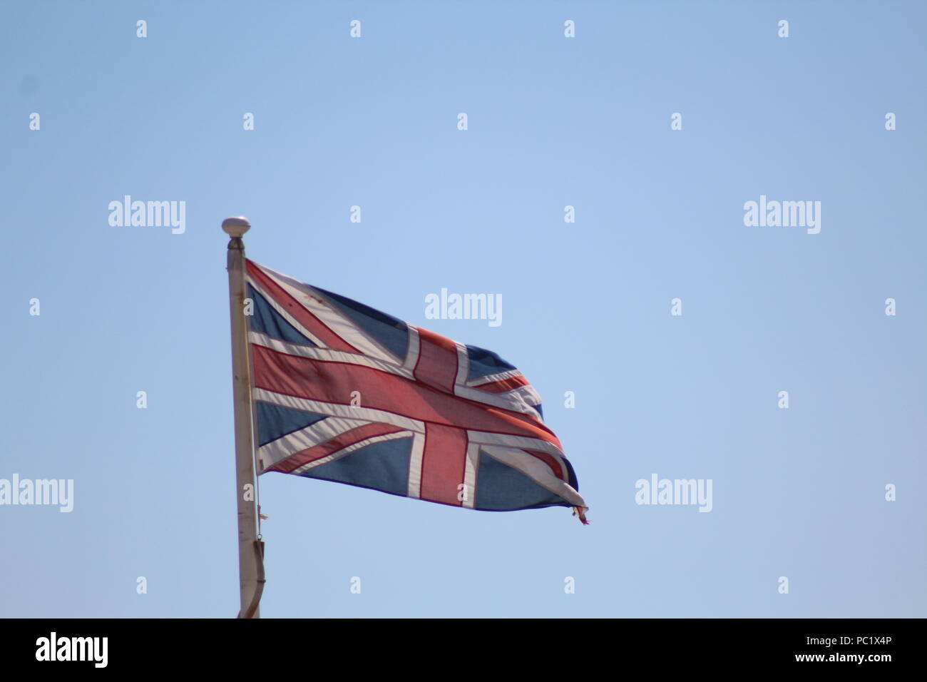 Union flag flying in blue skies Stock Photo