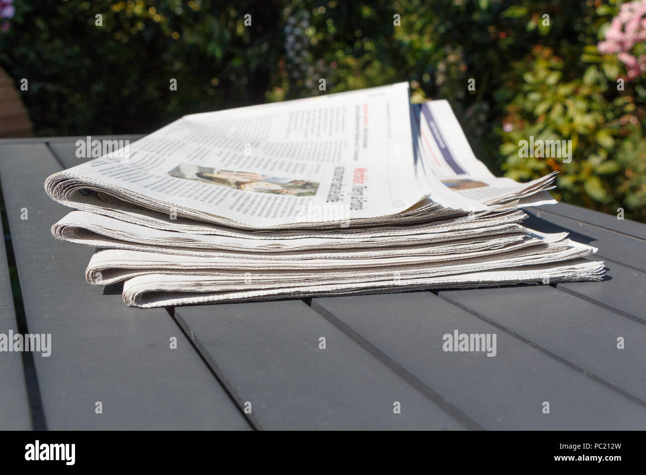 Pile of newspapers on a table in a garden Stock Photo Alamy