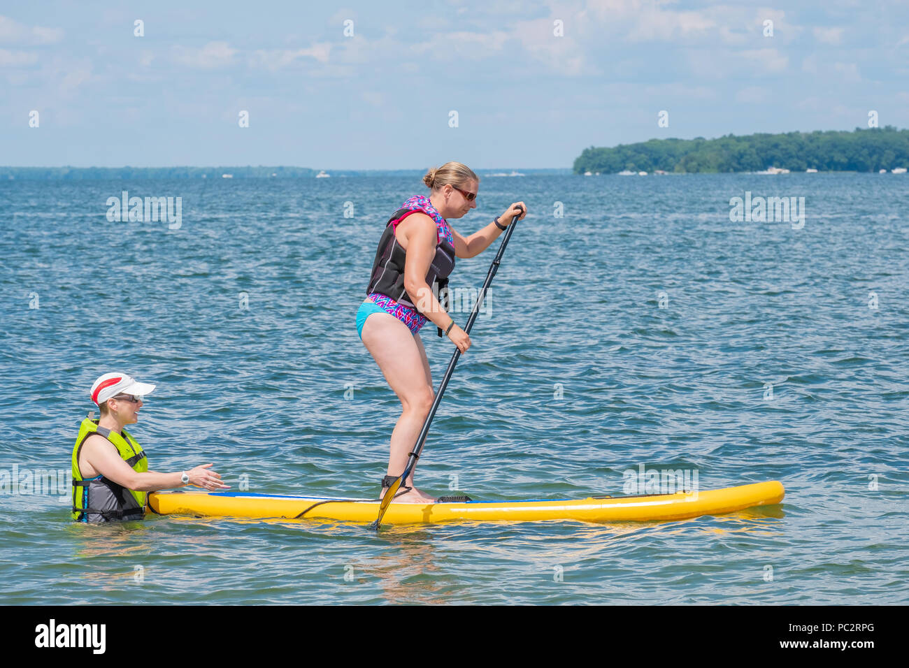 Woman learns the sport of paddleboarding on Lake Couchiching near Orillia Ontario Canada. Stock Photo