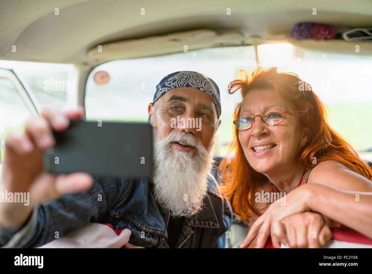 old hipster couple sitting in a van doing a selfie with a phone Stock Photo