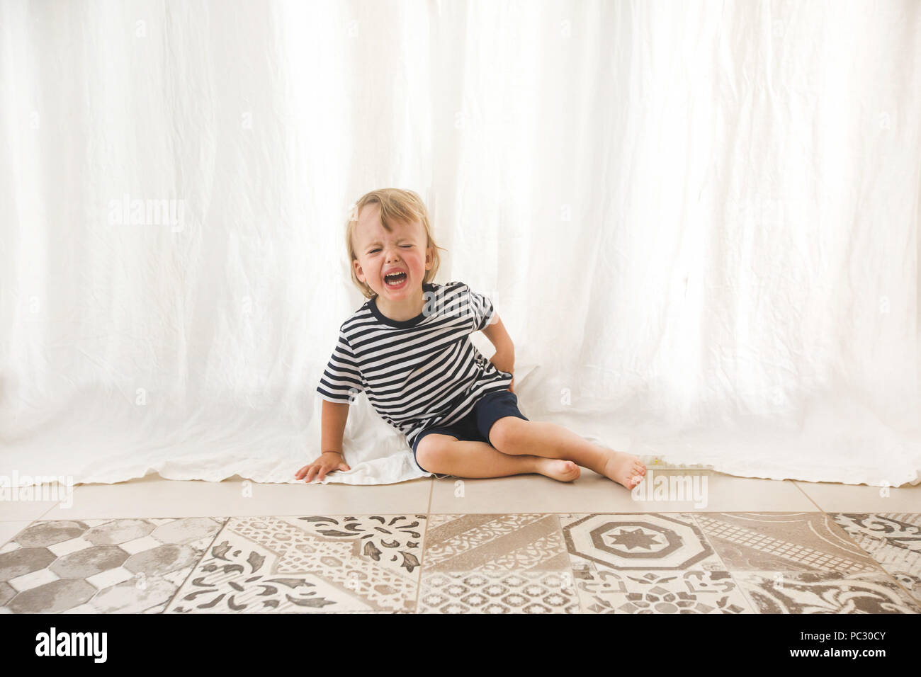 Screaming little boy crying on floor Stock Photo