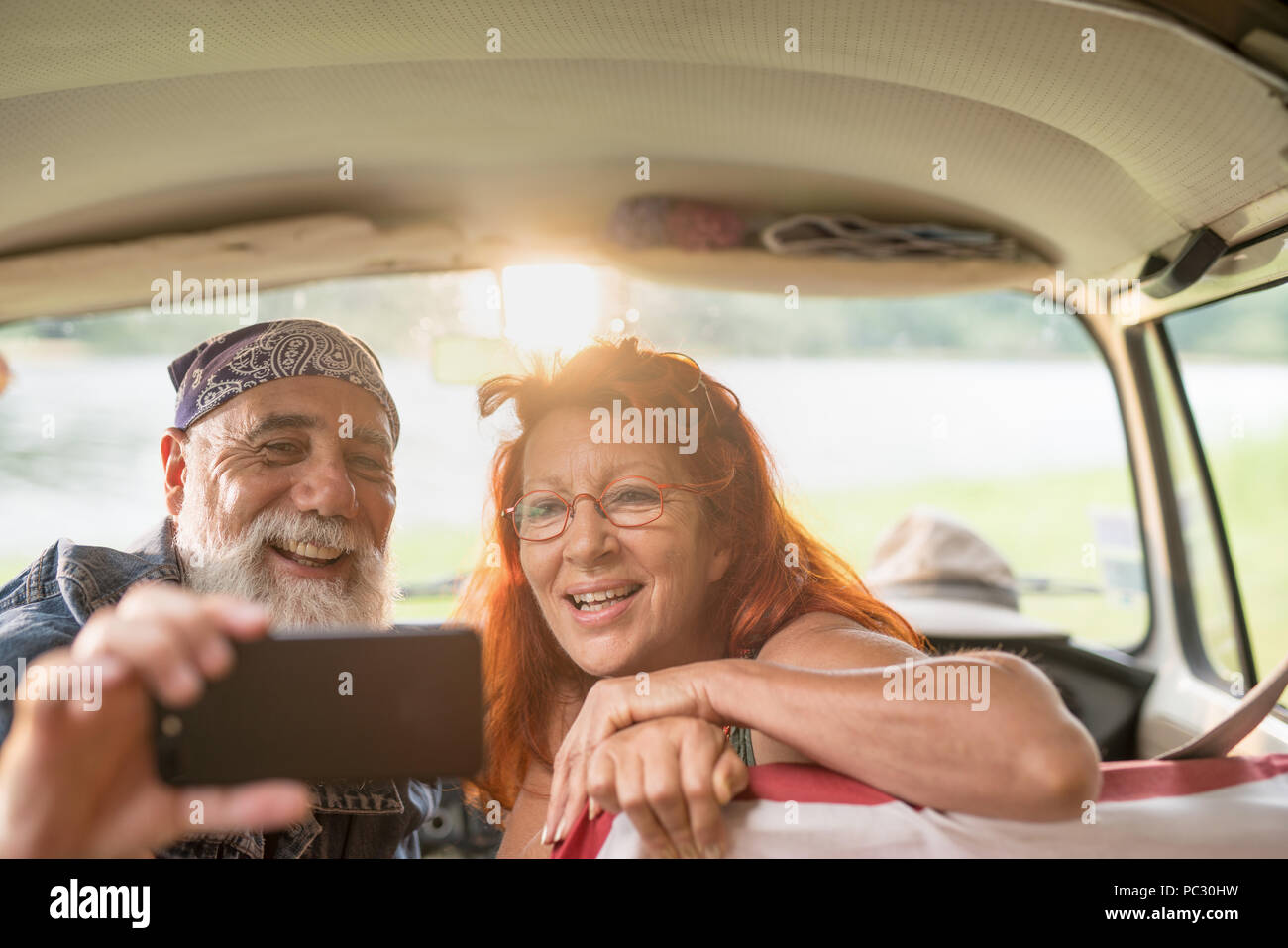 old hipster couple sitting in a car doing a selfie with a phone Stock Photo