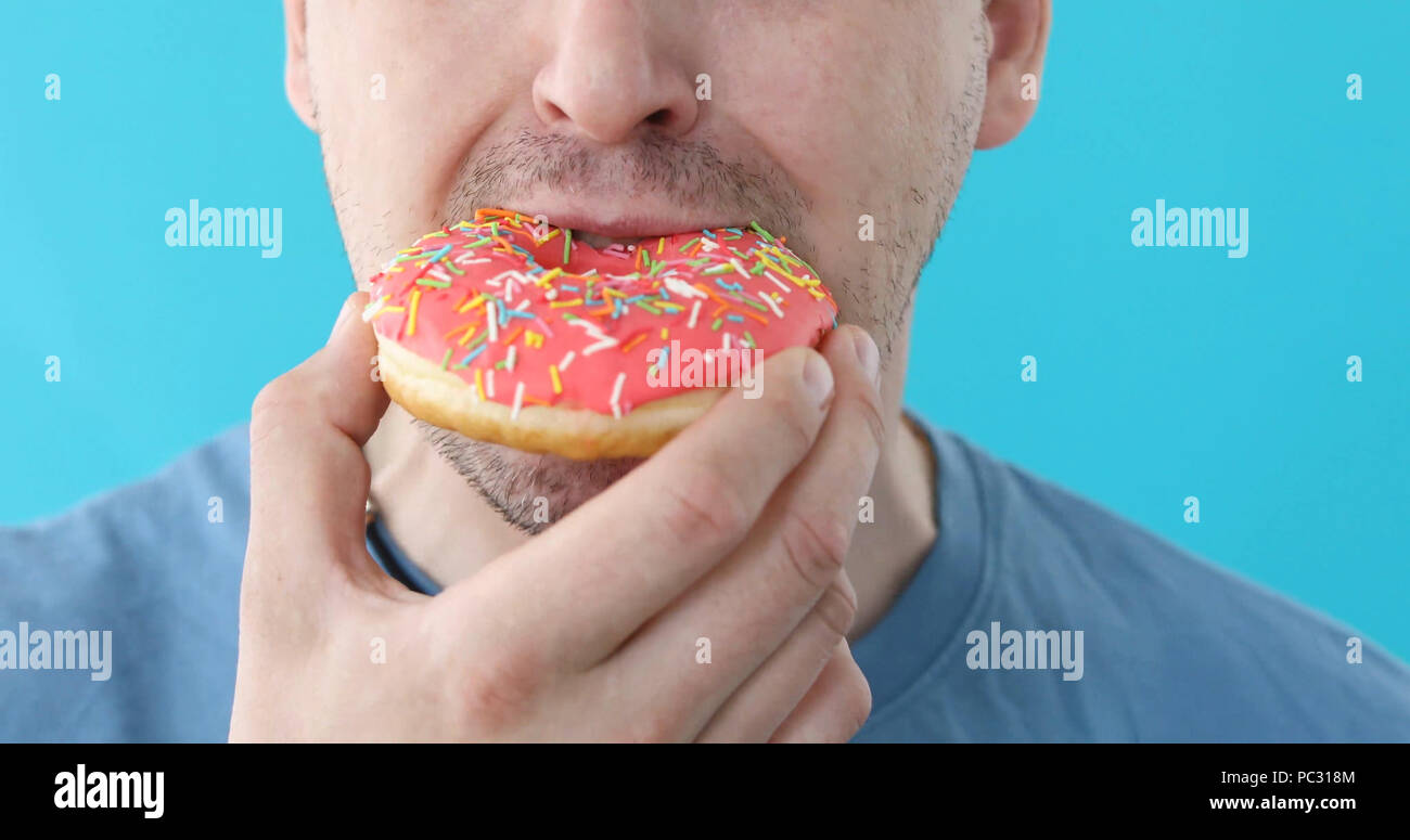 Man eat donut closeup on a blue background Stock Photo