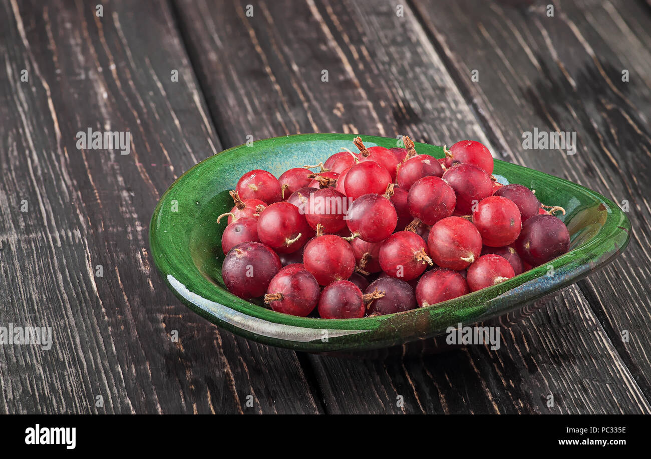 Red gooseberry in clay bowl Stock Photo