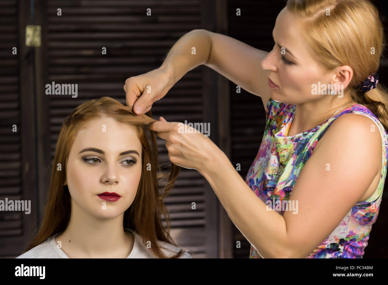 Hairdresser does hairstyle for young woman to weave braids. Concept