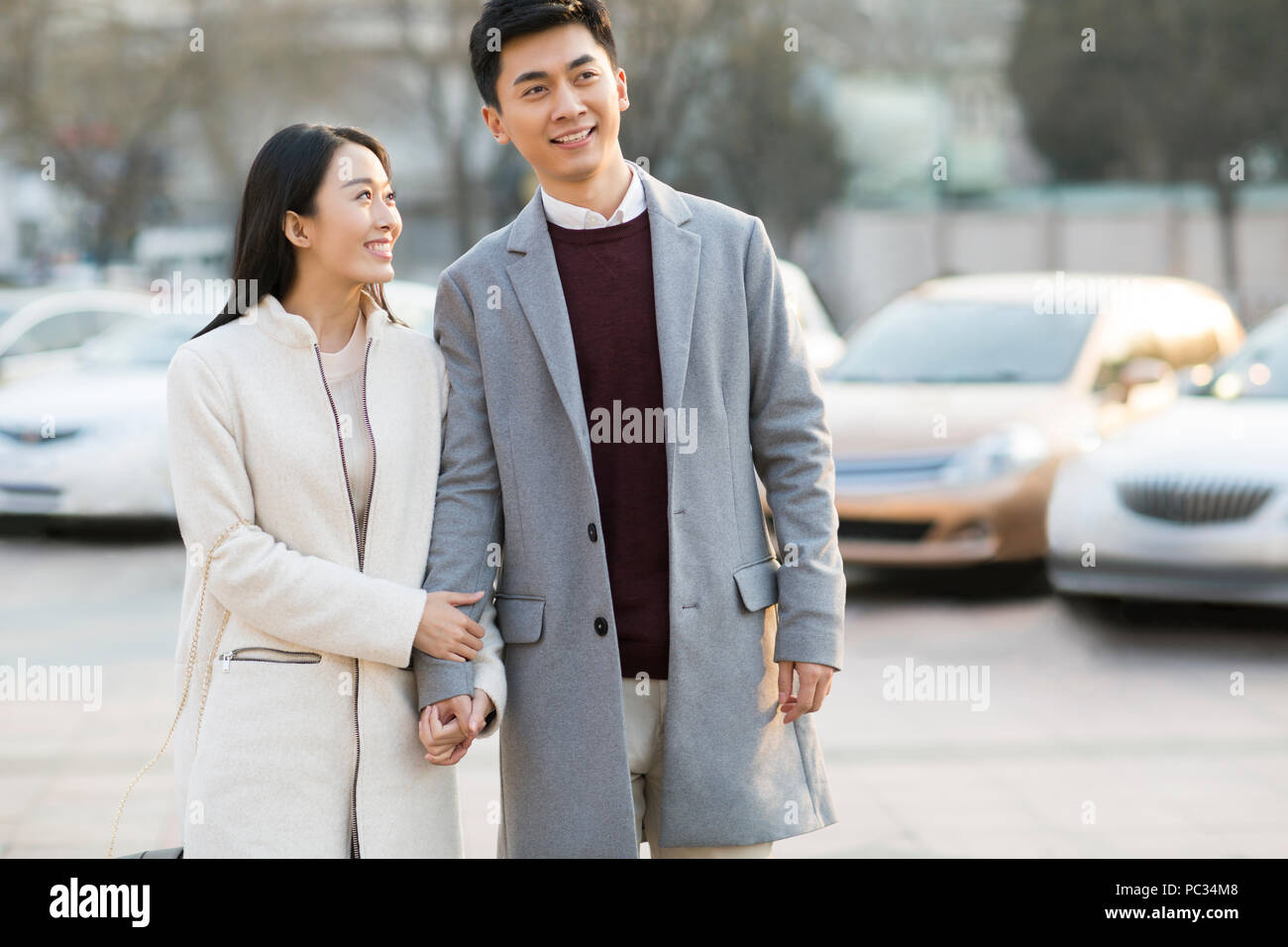 Cheerful young Chinese couple holding hands walking Stock Photo