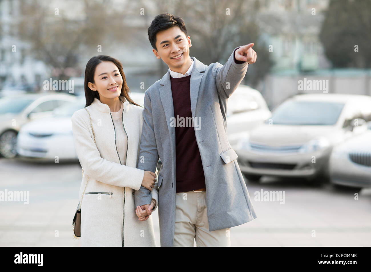 Cheerful young Chinese couple holding hands walking Stock Photo - Alamy