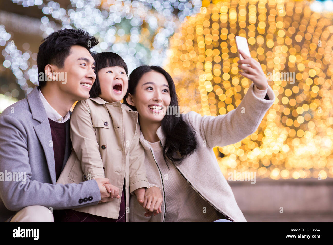 Cheerful young Chinese family taking self portrait with smart phone Stock Photo
