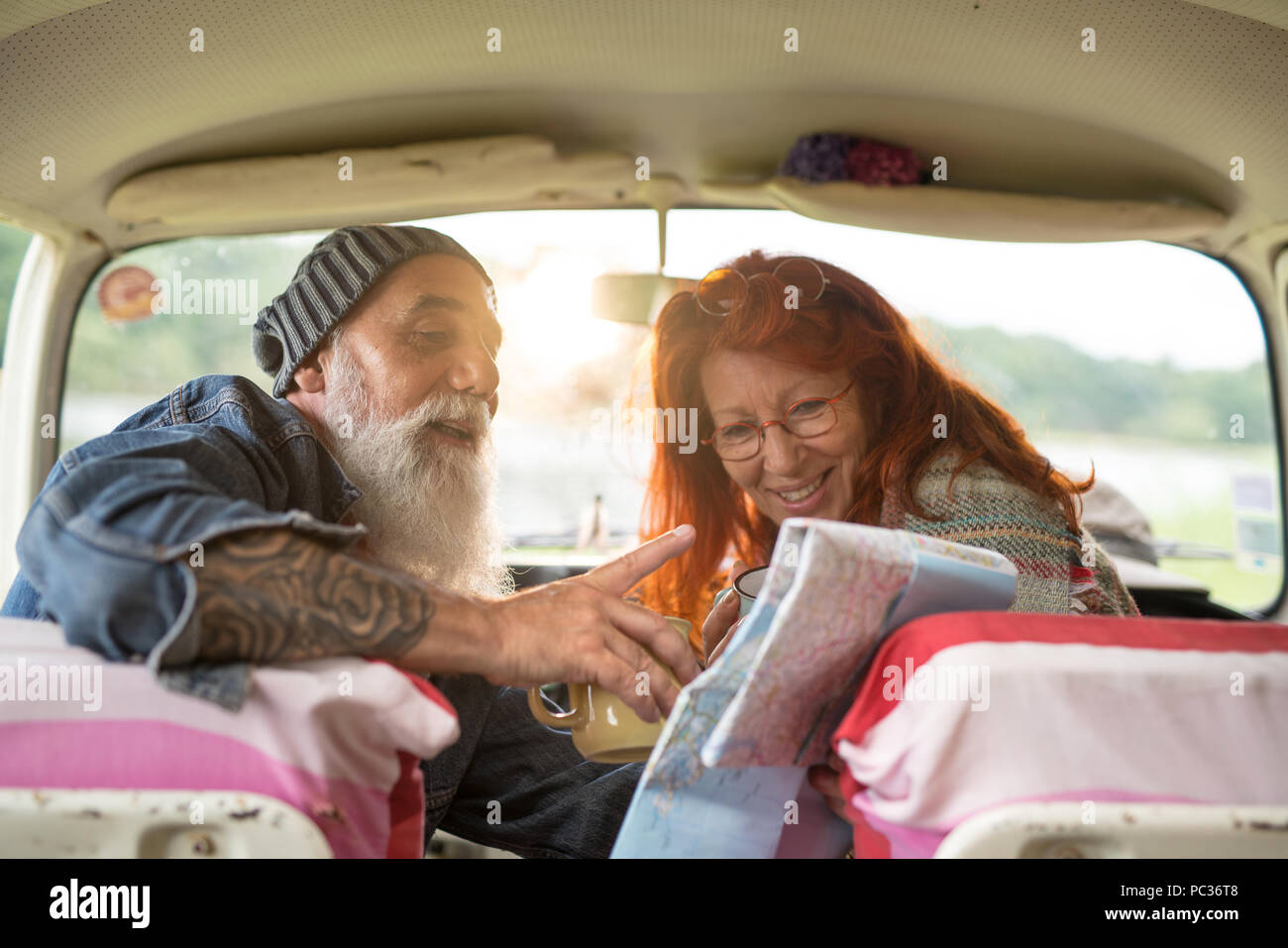 Old hipster couple sitting in a car and looking at a road map  Stock Photo