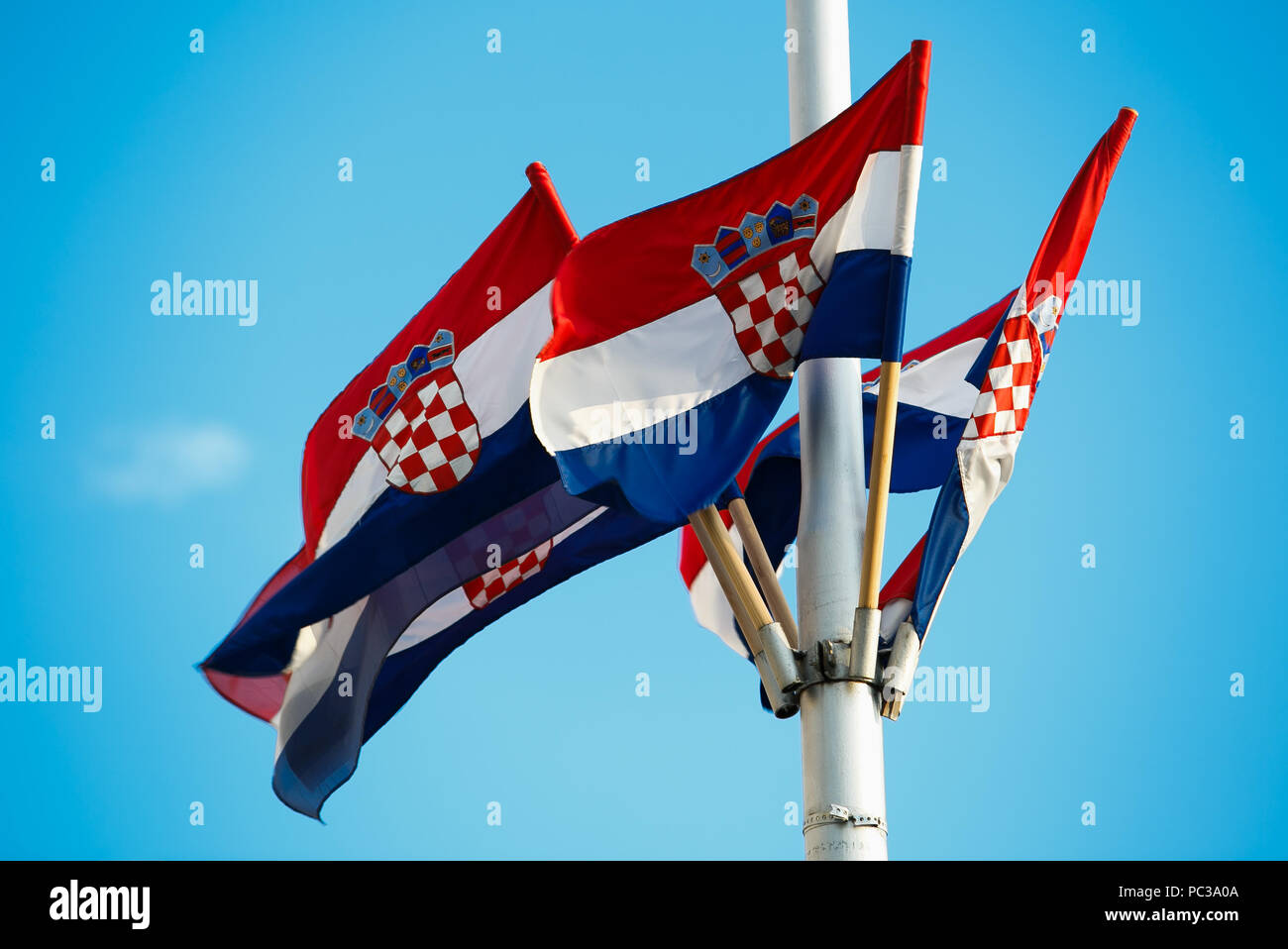 National flag of Crotia and Dalmatia region high on pole with bright blue sky on background.Traditional Croatian red,white and blue colors and symbols Stock Photo