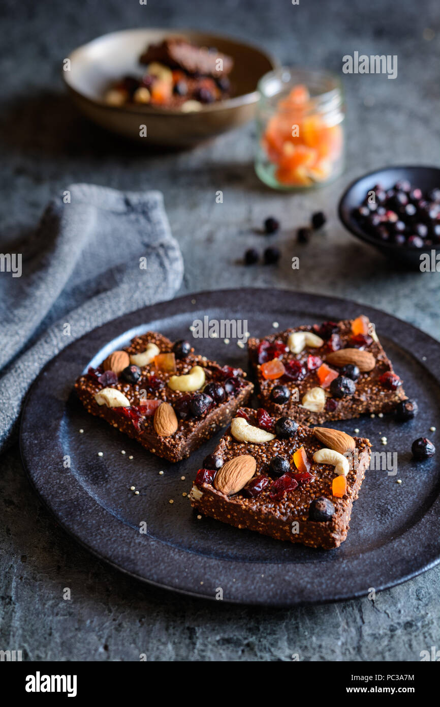 No bake chocolate puffed quinoa bars with freeze dried black currant, candied papaya, cashew nuts, almonds and cranberries Stock Photo