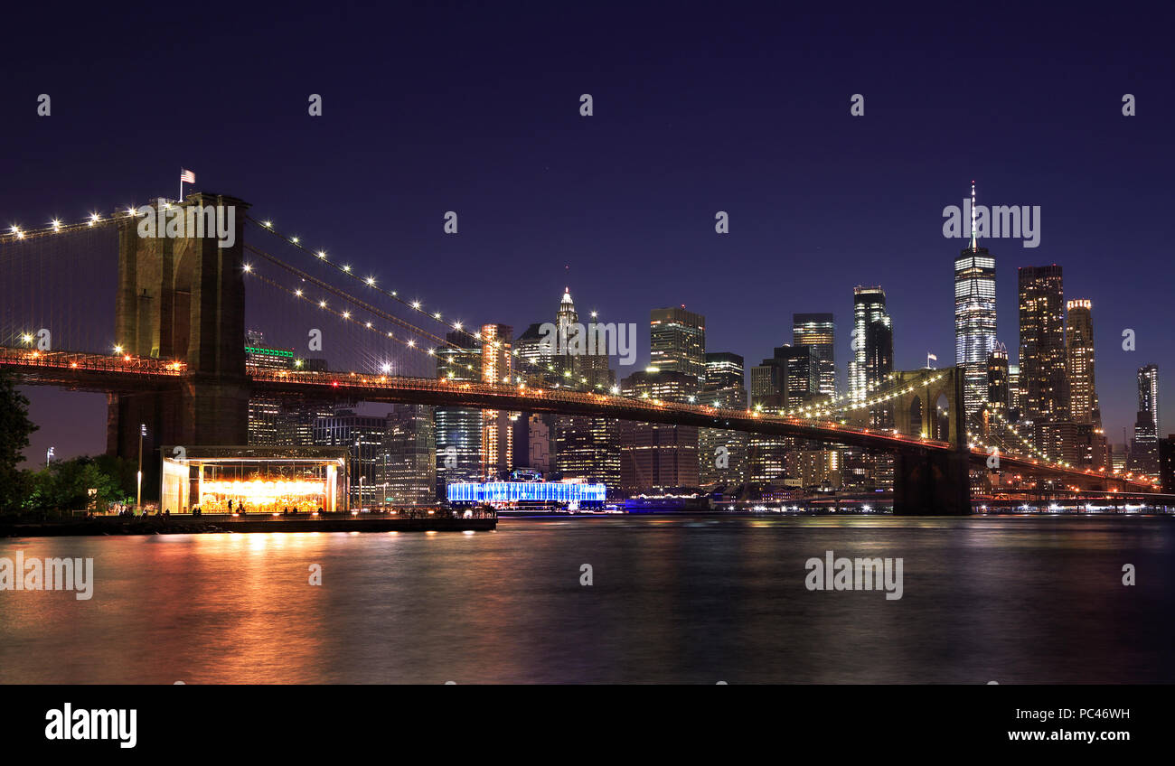 Panorama of Brooklyn Bridge and New York City (Lower Manhattan) with lights and reflections at dusk, USA Stock Photo