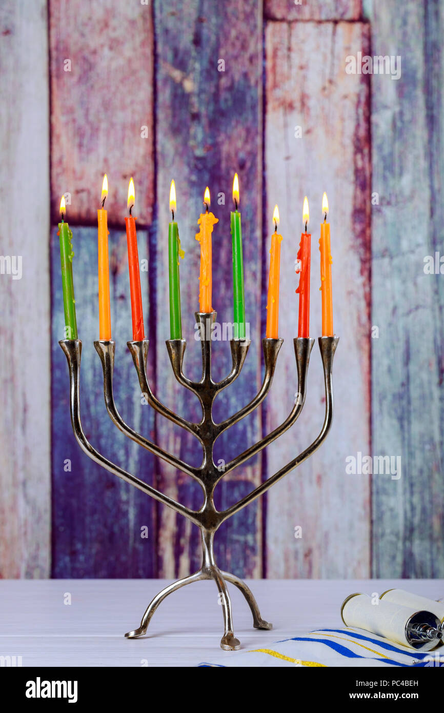 Hanukkah menorah with burning candles on wooden table front old vintage concrete wall Holiday concept. Stock Photo