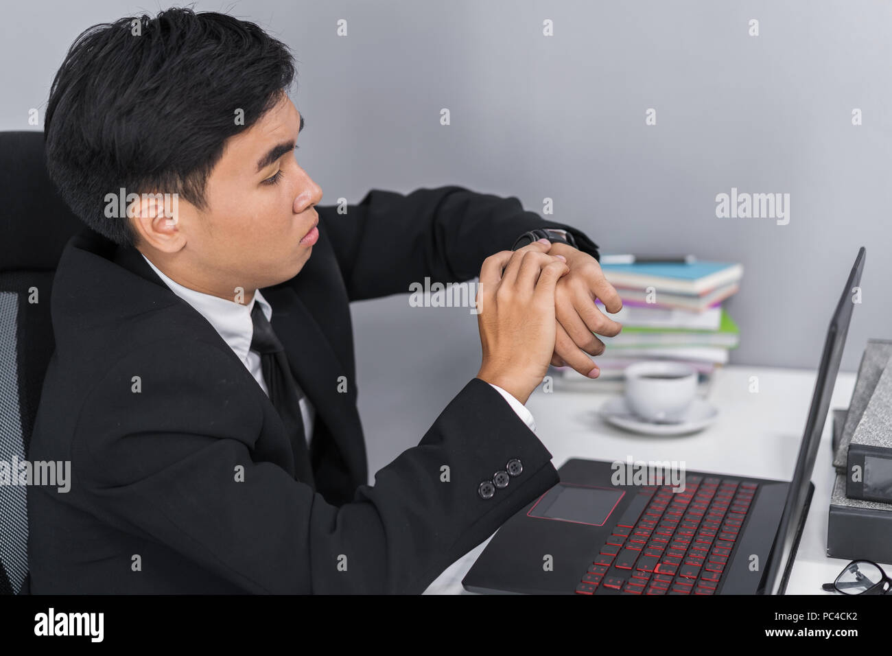 young business man checking time on watch while using laptop Stock Photo