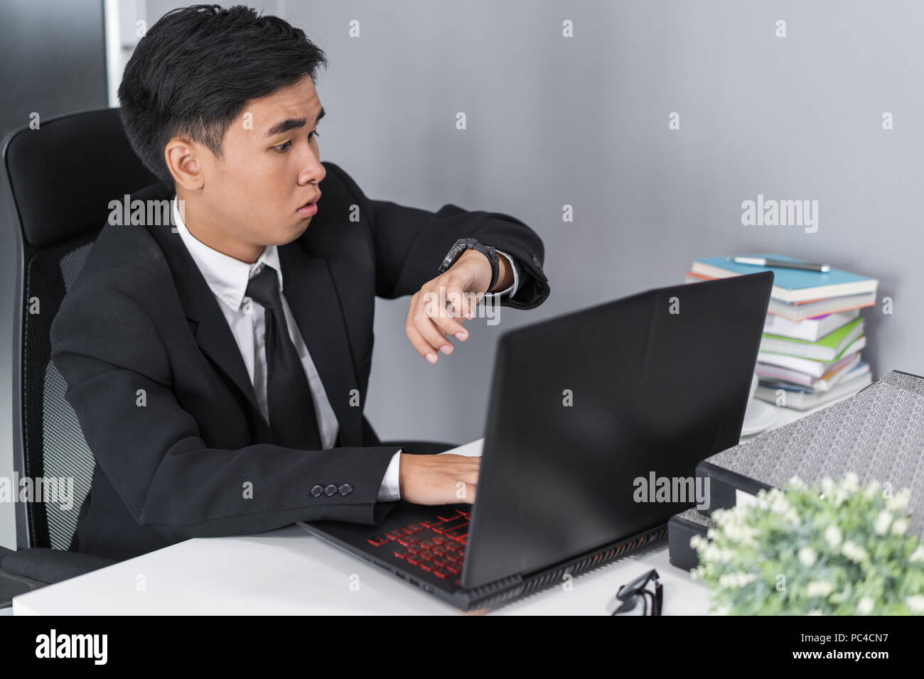 young business man checking time on watch while using laptop Stock Photo