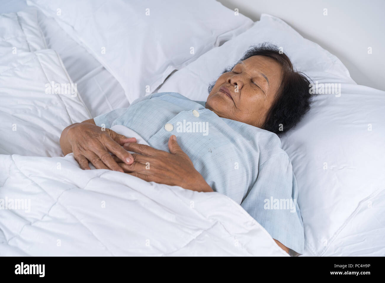 old woman sleeping on a bed in bedroom Stock Photo