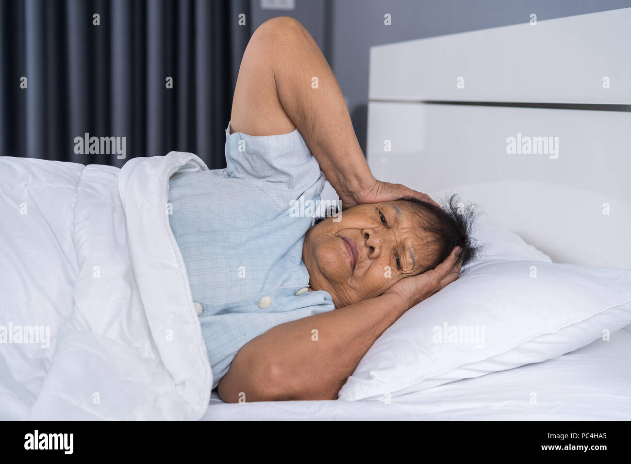 Old woman suffering from insomnia is trying to sleep in a bed Stock Photo