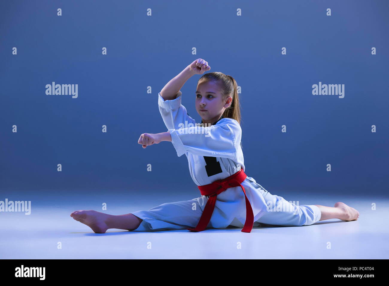Young girl training karate on blue background Stock Photo