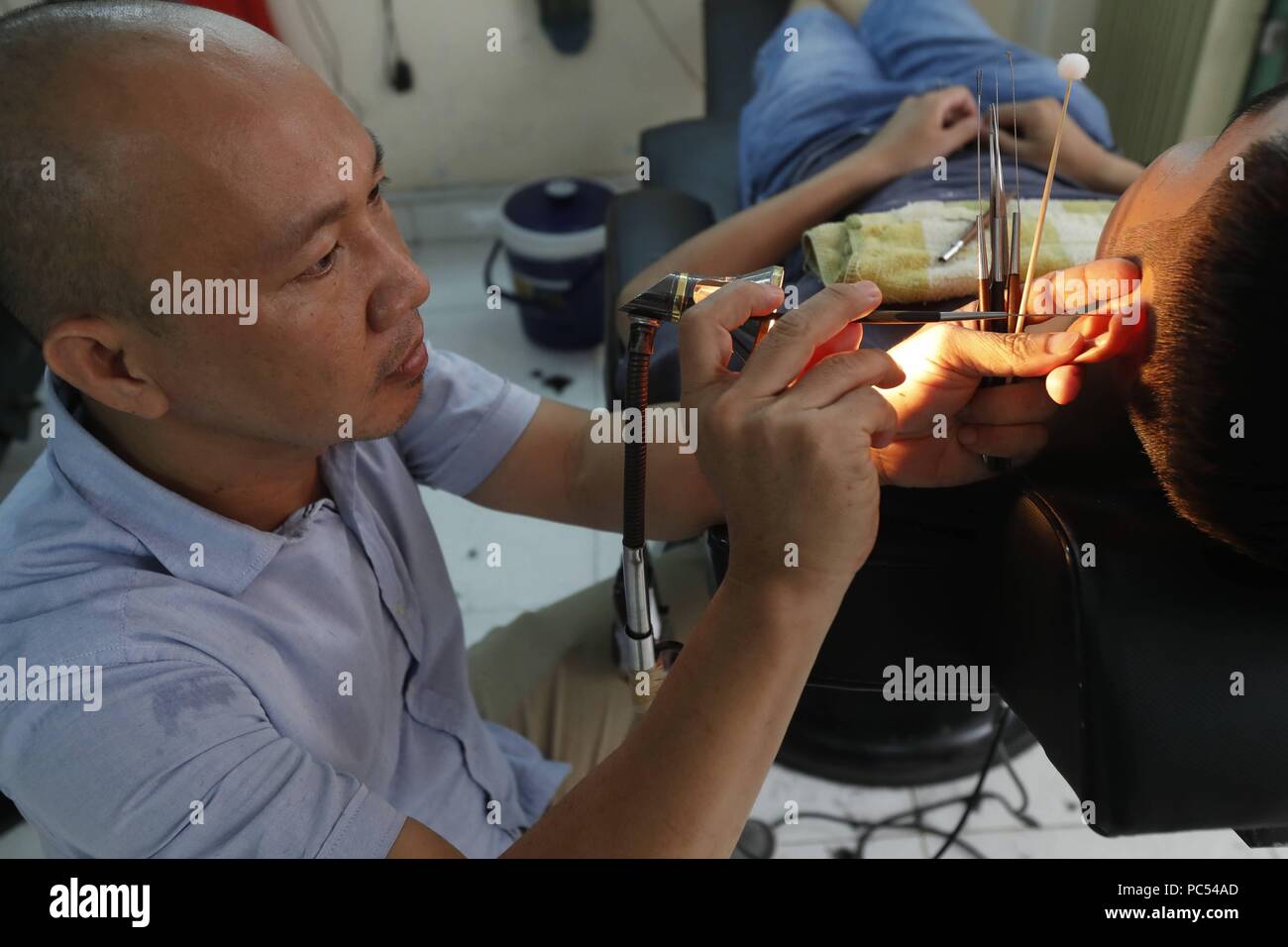 Vietnamese barber shop. Ear cleaning. Ho Chi Minh City. Vietnam