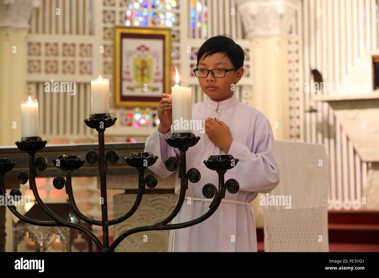 Dalat cathedral. Catholic mass. Altar boy with church candles. Dalat