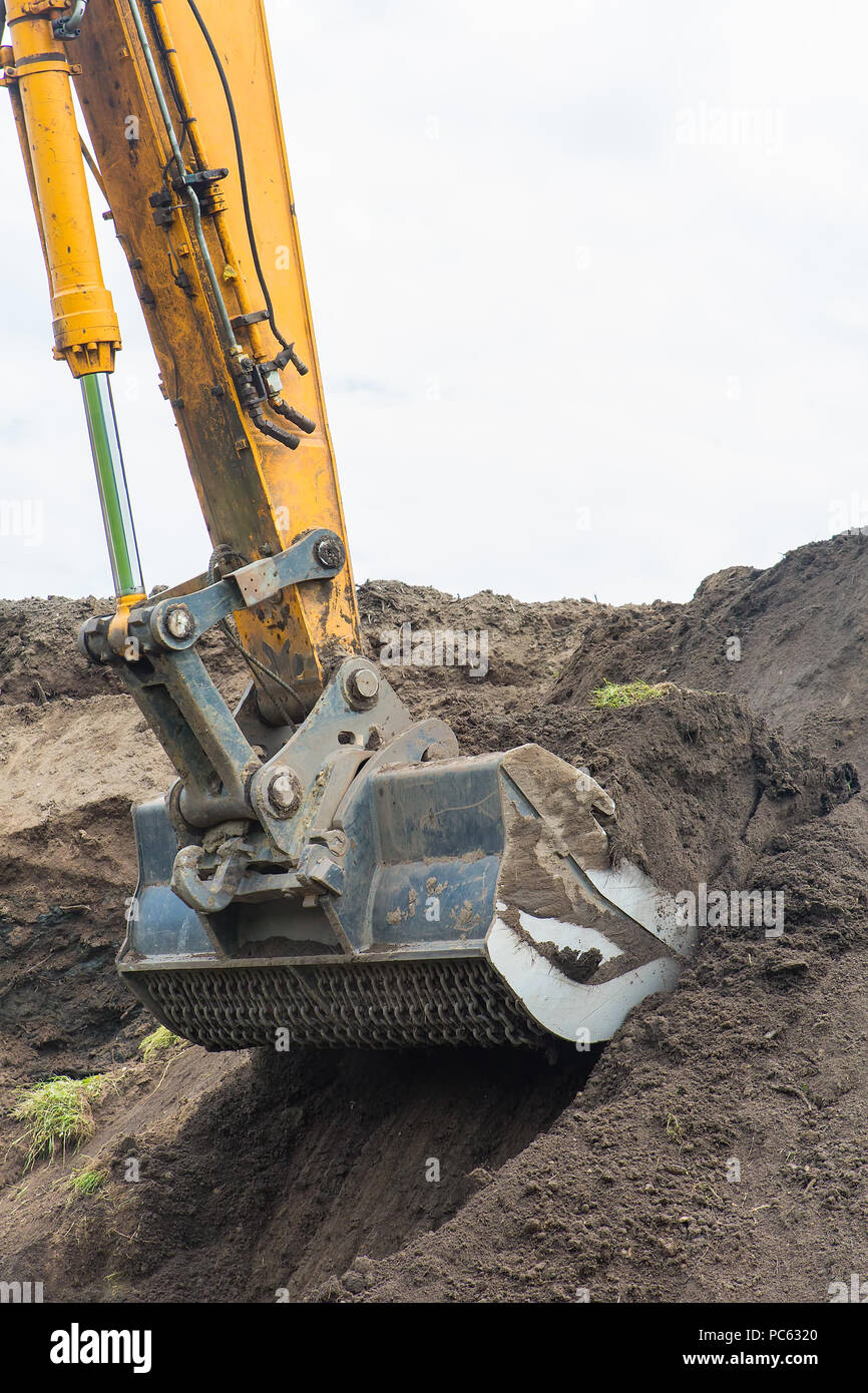 Excavator digs up ground from sandy hill Stock Photo
