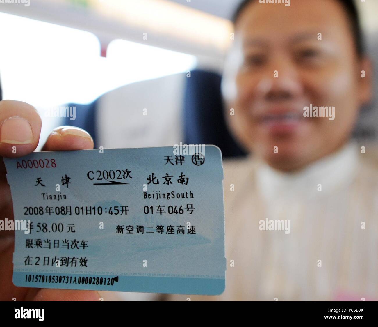 Beijing, China. 1st Aug, 2008. A passenger shows a train ticket for the Beijing-Tianjin high-speed intercity train in north China's Tianjin Municipality, Aug. 1, 2008. Credit: Wang Yebiao/Xinhua/Alamy Live News Stock Photo