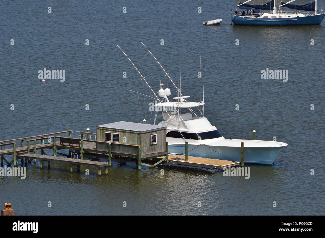 Coastal Living Blue and White Boat Docked at Pier on Calm Florida Water Stock Photo
