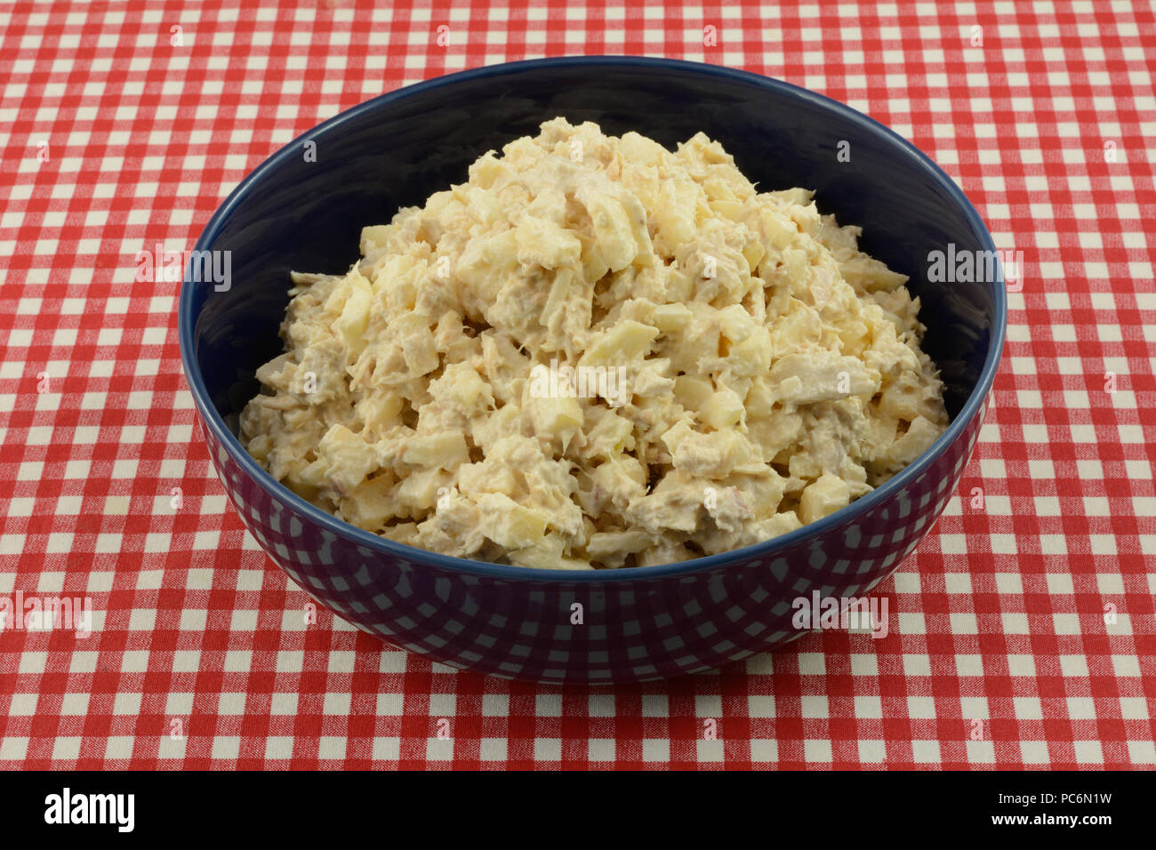 Albacore tuna fish salad made with chopped apple in blue serving bowl on red checkered tablecloth Stock Photo