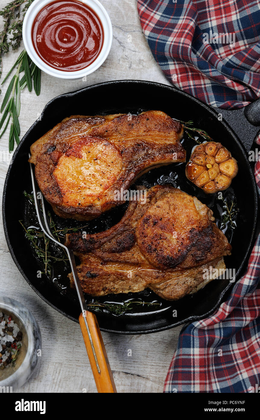 Roasted pork loin steak in a frying pan with tomato sauce Stock Photo