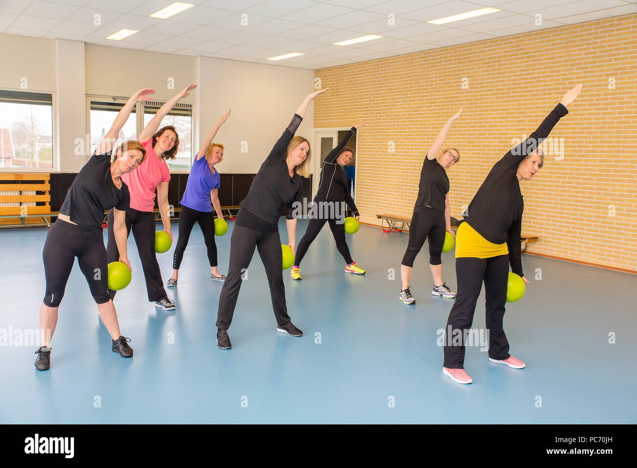 Group of women with balls doing stretching exercises in gym class Stock Photo