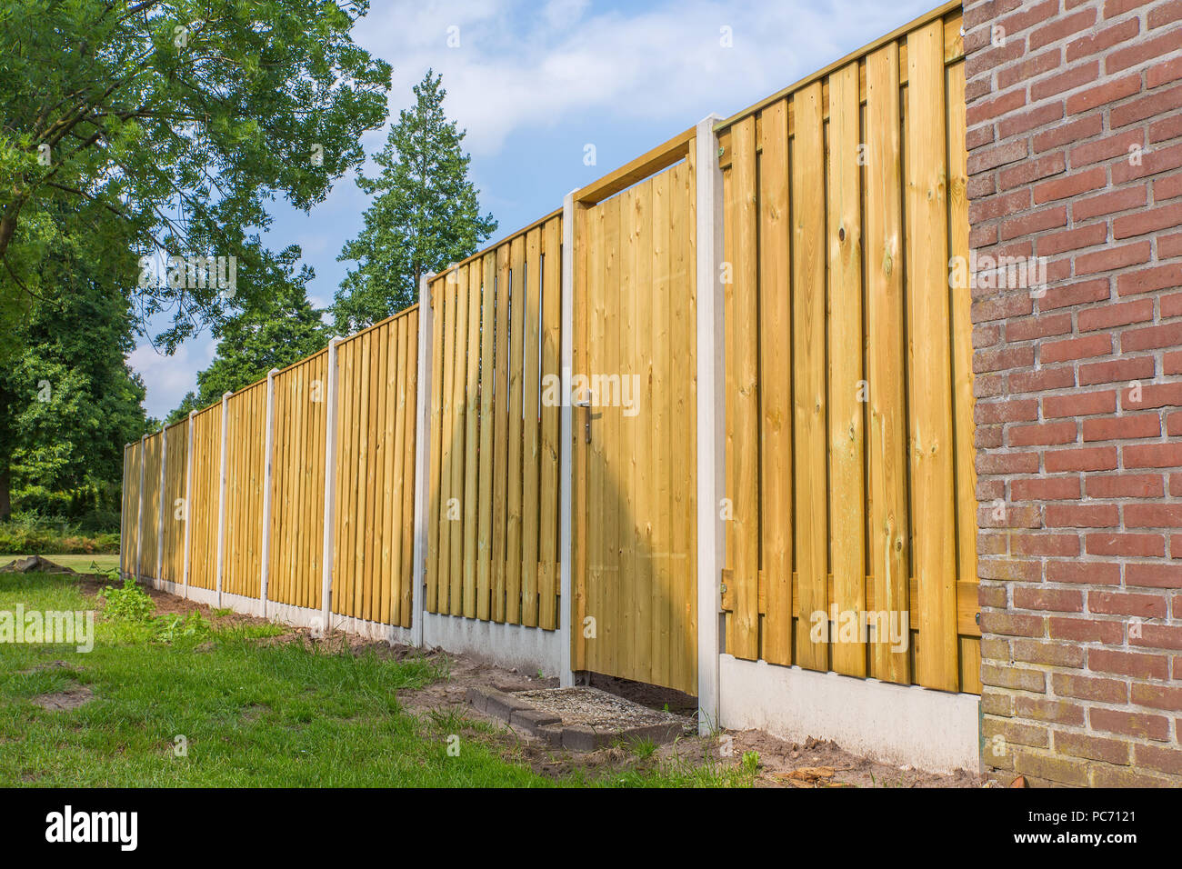 New wooden fence construction with stone wall and trees Stock Photo