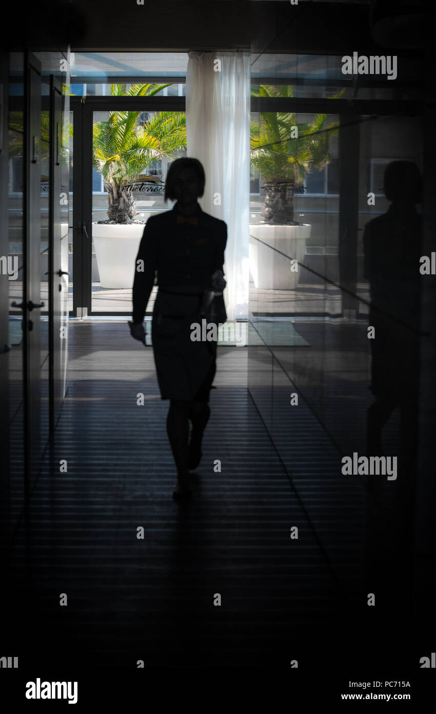 Female silhouette in the backlight, in the glass corridor Stock Photo