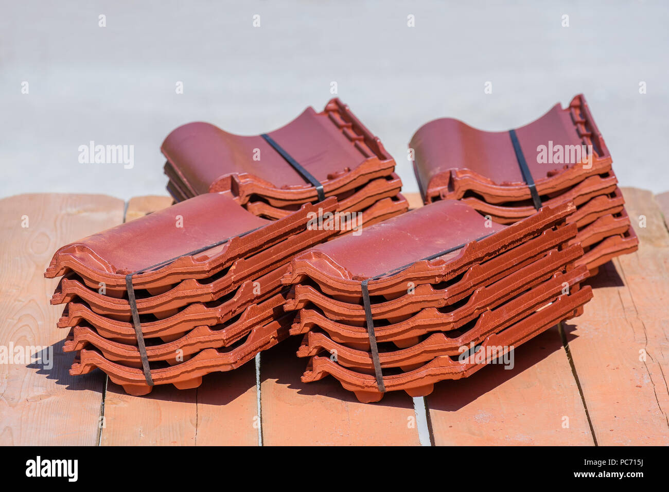 Stacks of new roof tiles lie on wooden scaffold boards Stock Photo
