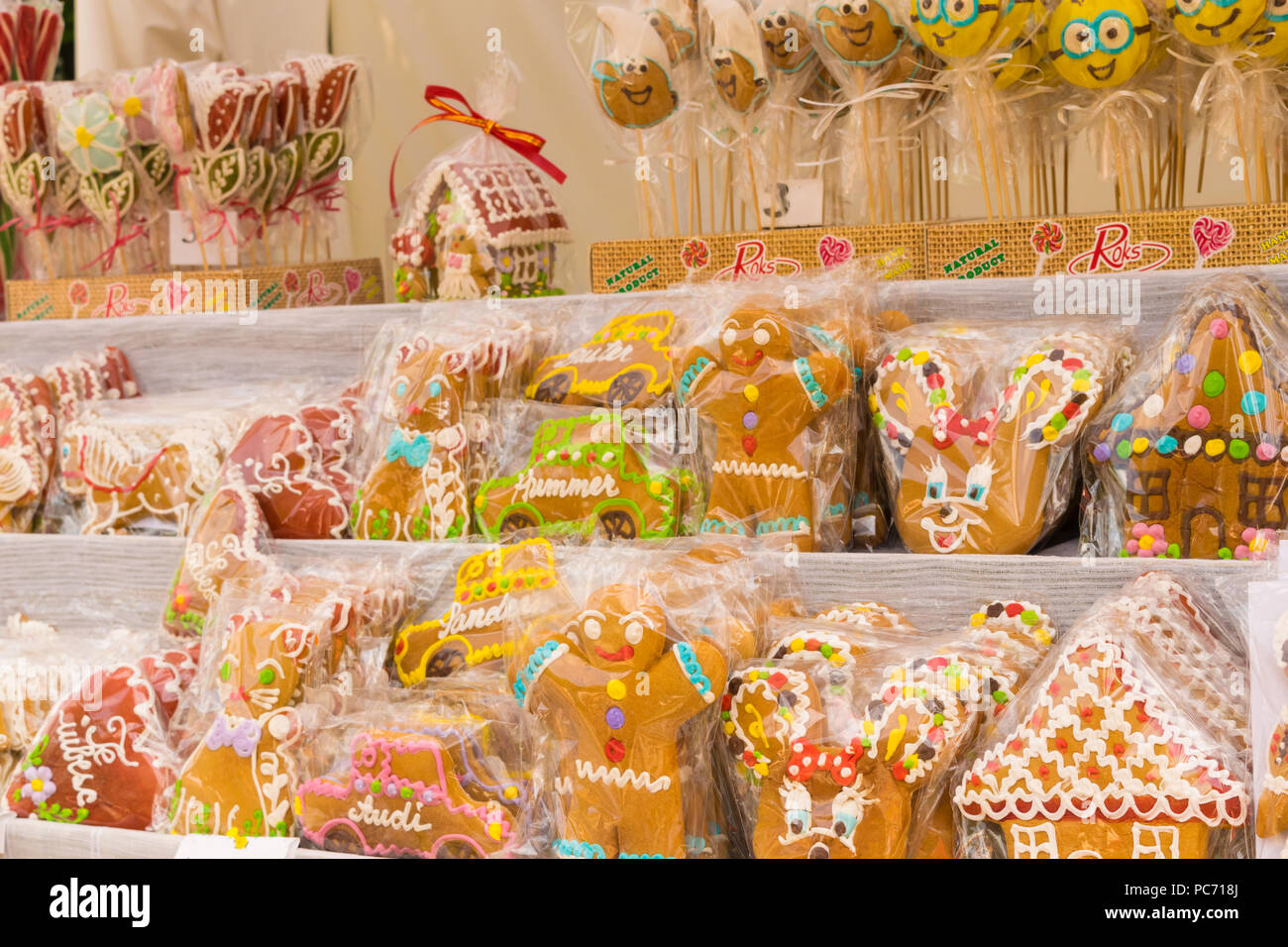 Gingerbreads in heart, car, house, cartoon characters and gingerbread man shapes displayed for sale and wrapped in protective plastic foil. Stock Photo