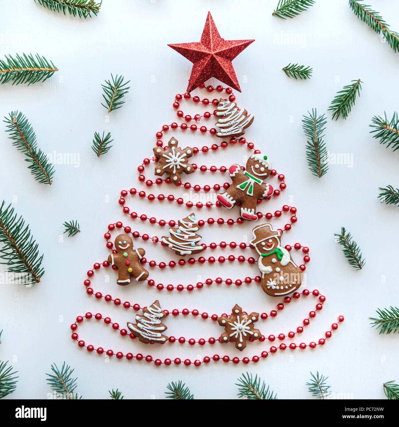 Creative idea for Christmas or New Year theme. A Christmas tree made of beads decorated with traditional gingerbread and a star on top. Celebratory concept. Stock Photo