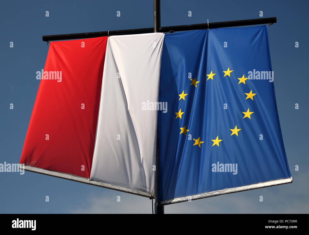 National flag of Poland and flag of European Union hang out together, next to each other, on pole, outdoor, in background blue sky Stock Photo
