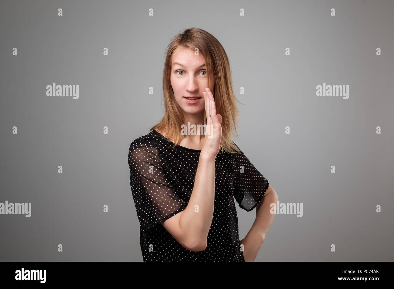 Portrait of a young pretty woman telling secret information, holding her hand near mouth Stock Photo