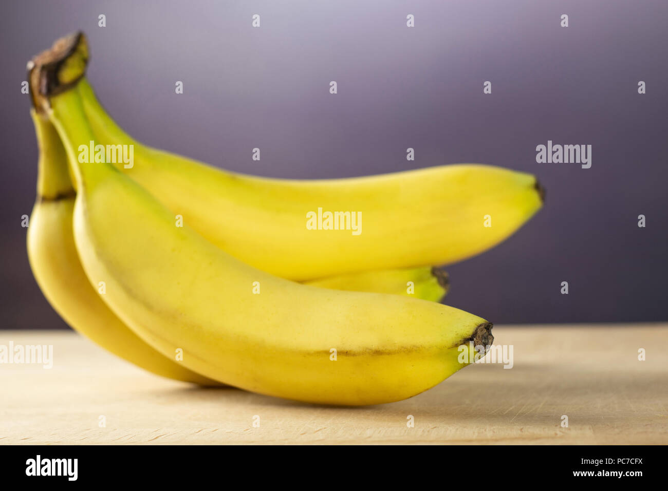 Group of five whole fresh yellow banana one cluster with grey gradient behind Stock Photo