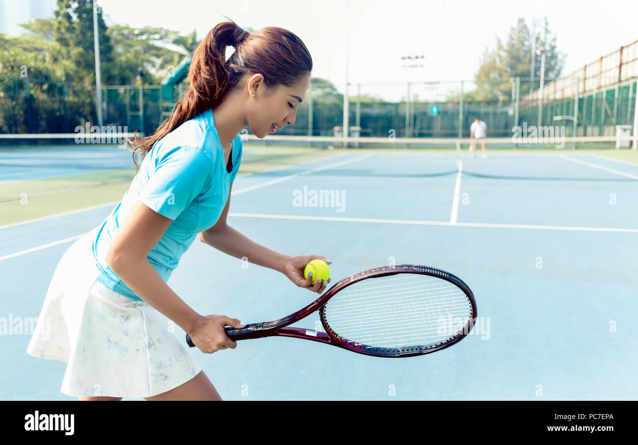 Professional female player smiling while serving during tennis match Stock Photo