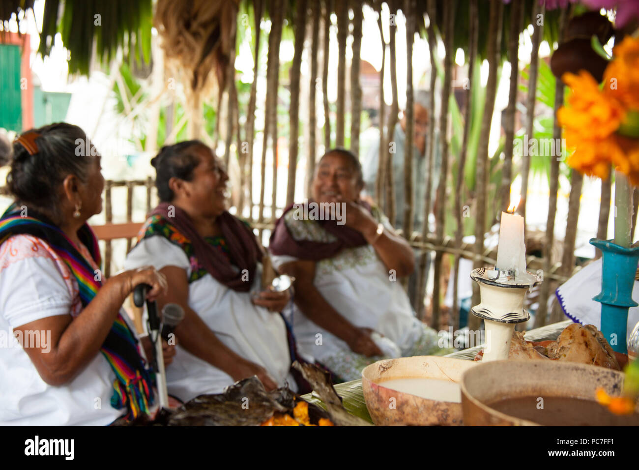 Mestizas laughing and  having a conversation in a 'choza' where the Hanal Pixan Altar is located. Stock Photo